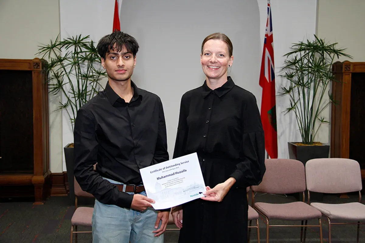 muhammad receiving a certificate of outstanding service from the manitoba minister of education